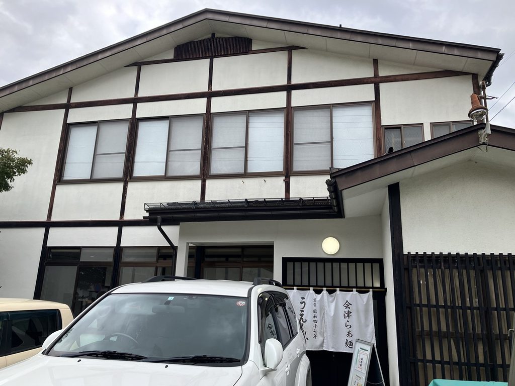 会津若松のラーメン店うえんで山鹿店の外観。白い建物と入口に掛かった会津らぁ麺の暖簾